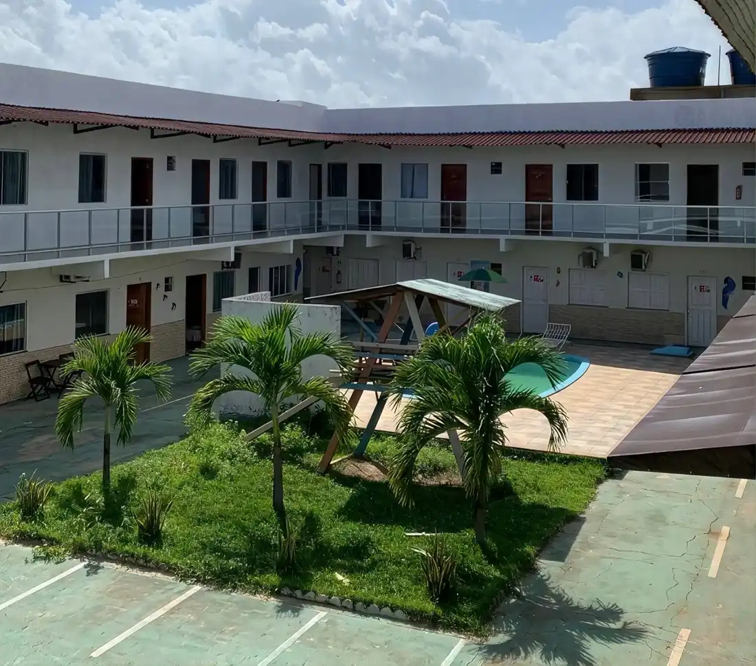 Pátio interno da pousada com palmeiras e a piscina logo abaixo